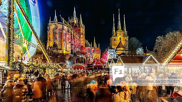 A busy Christmas market with an illuminated Ferris wheel and a cathedral in the background at night  Erfurt Christmas Market Erfurt
