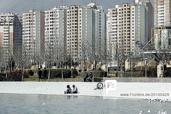 A young couple sits on the beach of Lake Chitgar in Tehran  Iran. Lake Chitgar is a man-made lake in the north-west of Tehran  also known as the Lake of the Martyrs of the Persian Gulf  10 March 2019