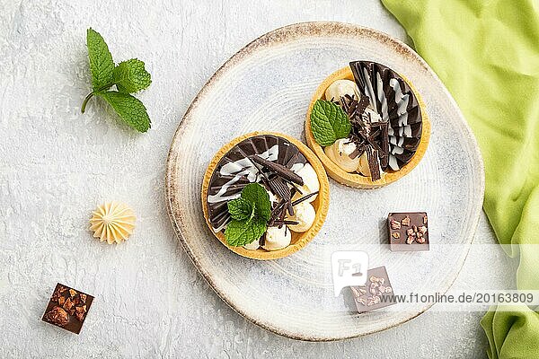 Süße Törtchen mit Schokolade und Käsecreme mit einer Tasse Kaffee auf einem grauen Betonhintergrund und grünem Textil. Draufsicht  Flat Lay  Nahaufnahme