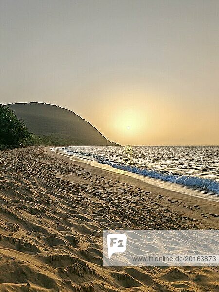 Blick über einen Strand  die Küste und das Meer im Sonnenuntergang. Im Vordergrund der leere Sandstrand von Grande Anse  Basse Terre  Guadeloupe  Französische Antillen  Karibik  Nordamerika