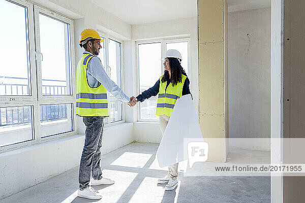 Multiracial engineers shaking hands standing at construction site