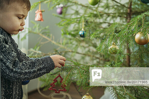 Cute boy decorating Christmas tree at home
