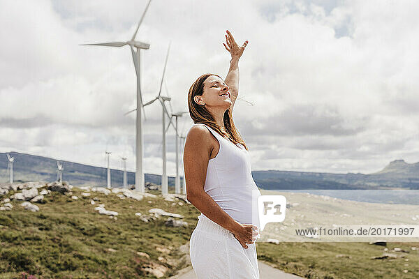 Spain  Madrid  Portrait of pregnant woman standing in front of wind farm turbines