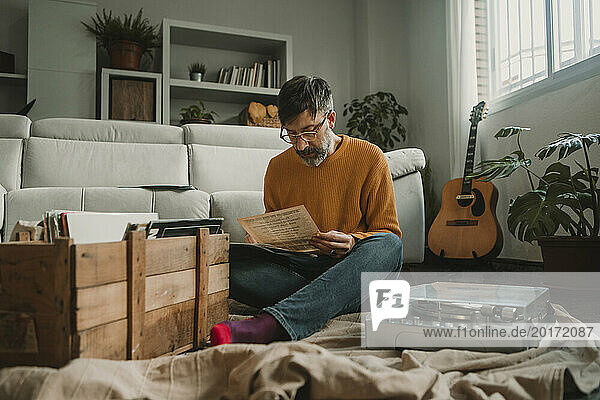 Man reading paper sitting by record player at home