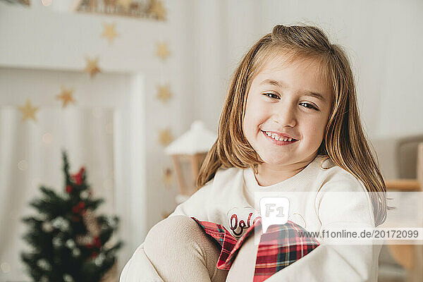 Smiling cute blond girl sitting at home