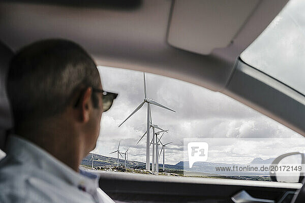 Spain  Madrid  Man sitting in car looking at wind farm turbines