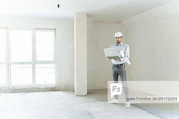 Happy architect using laptop at site