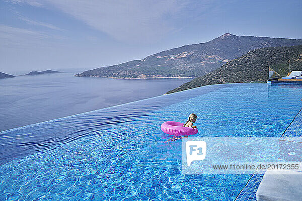 Girl swimming in blue pool at villa