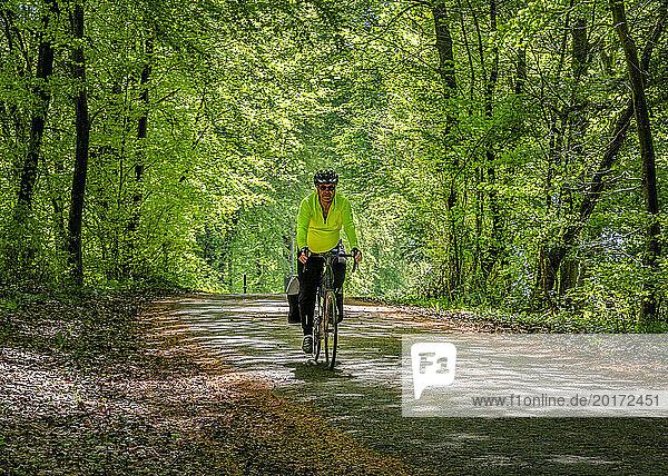 Senior man cycling on Avenue Verte cycle route in forest