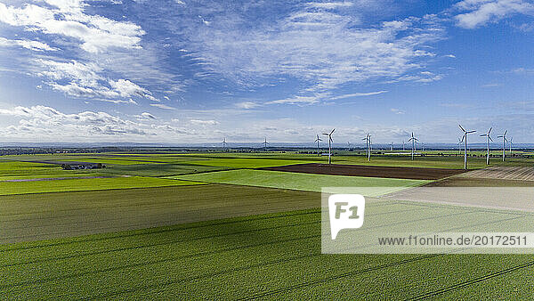 Aerial view of countryside fields with wind farm in background