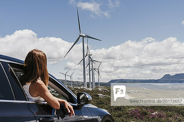 Spain  Madrid  Woman leaning out of car window looking at wind farm turbines