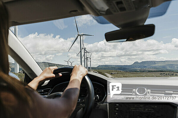 Spain  Madrid  Hands of woman driving past wind farm