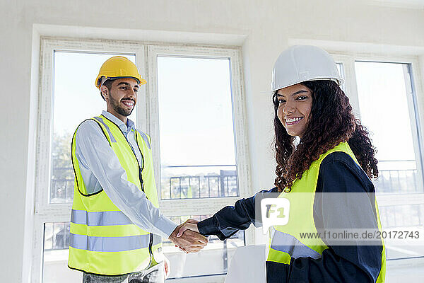 Happy engineer shaking hand with colleague at site