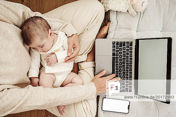 Freelancer working on laptop with baby daughter sleeping at home