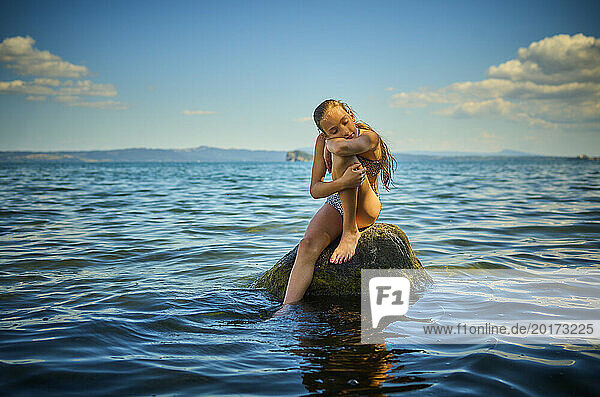 Girl resting on rock in lake Bolsena  Italy
