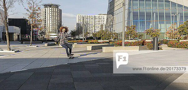 Happy man skateboarding in city on sunny day