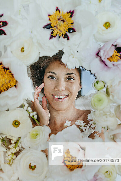 Smiling woman lying under glass surface with flowers