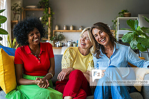 Happy mature woman having fun with friends sitting on sofa at home