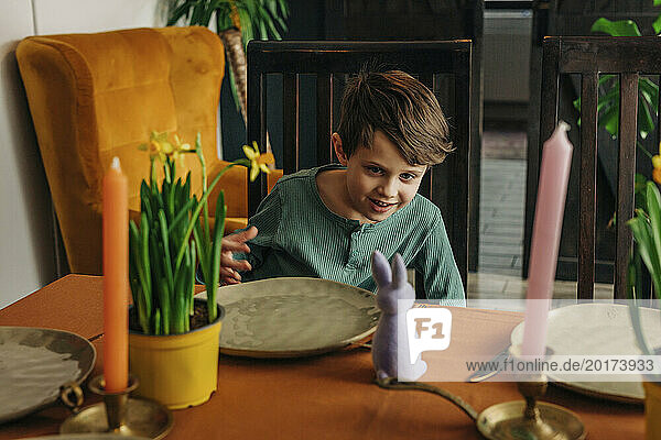 Smiling boy looking at Easter bunny at dining table in home