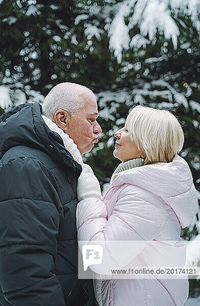 Man puckering lips to woman in warm clothes