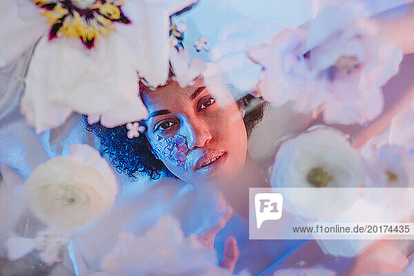 Beautiful woman lying behind glass surface with flowers