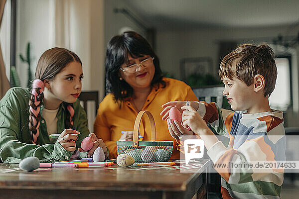 Family decorating Easter eggs at table