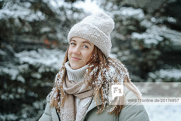 Smiling woman wearing knit hat on snow in winter