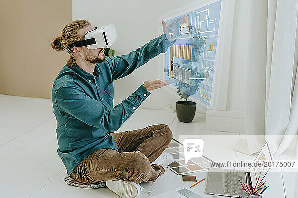 Interior designer preparing project through VR glasses sitting on floor at office