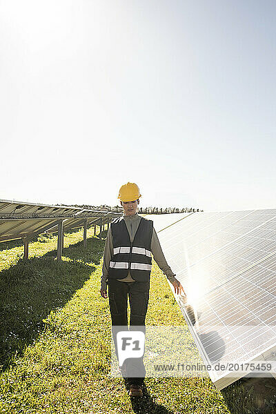 Female maintenance engineer walking near solar panels at power station
