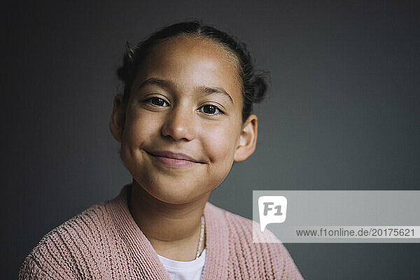 Portrait of girl smiling against gray background