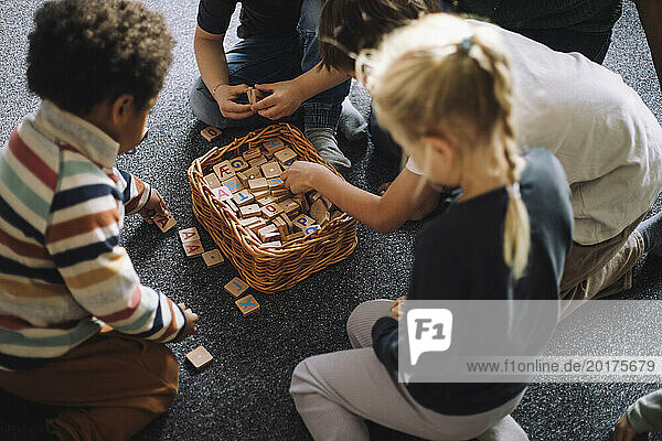 High angle view of preschool kids playing puzzle game while sitting in classroom at day care center