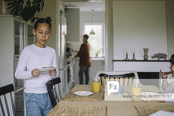 Girl setting up table for breakfast at home