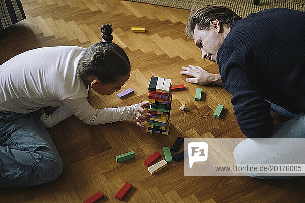 High angle view of father and daughter playing toy blocks on floor at home