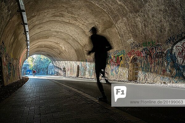 Ein Jogger bewegt sich durch einen Tunnel mit Graffiti und dynamischen Schatten  Nordbahntrasse  Elberfeld  Wuppertal  Bergisches Land  Nordrhein-Westfalen