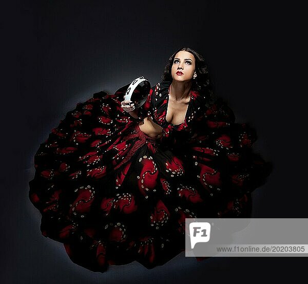 Junge süße Frau sitzen in Zigeuner schwarz und rot Kostüm isoliert