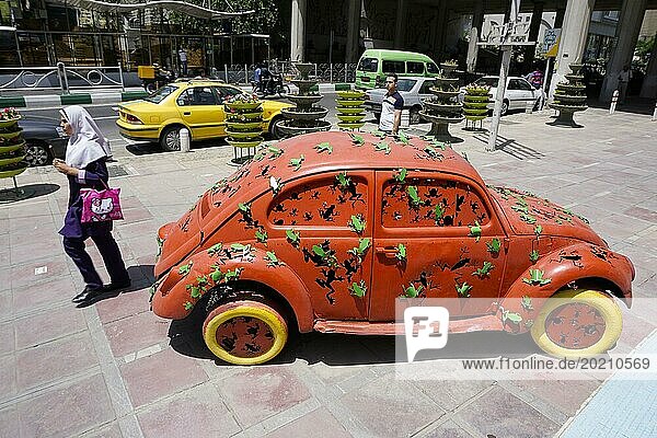 Eine Frau läuft in Teheran an einem Volkswagen Käfer Kunstobjekt der auf dem Gehweg steht vorbei. Die Stadt Teheran verändert das Bild der Stadt durch Kunstobjekte im öffentlichen Raum  17.05.2016