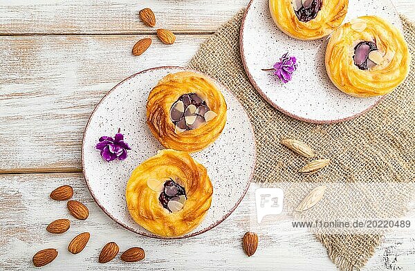 Small cheesecakes with jam and almonds with cup of coffee on a white wooden background and linen textile. top view  flat lay  close up