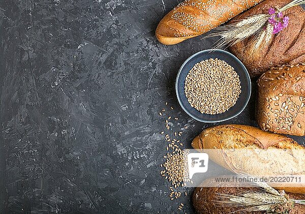 Verschiedene Arten von frisch gebackenem Brot auf einem schwarzen Betonhintergrund. Draufsicht  Flat Lay  Copy Space