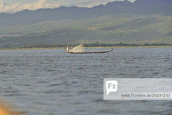Einsamer Fischer auf einem Boot zieht ein Netz im ruhigen Gewässer  Inle See  Myanmar  Asien