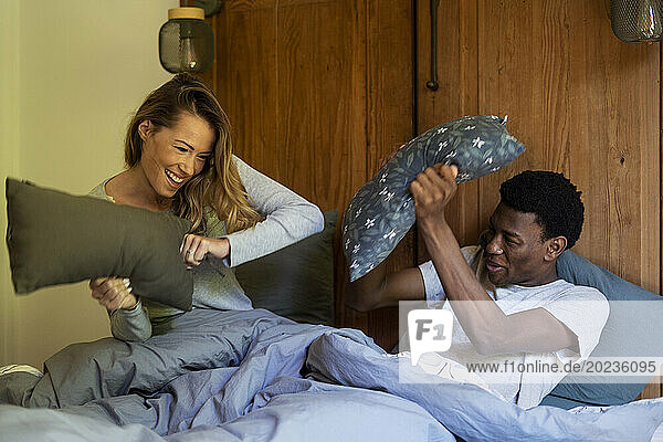 Adult couple having a pillow fight while lying on bed