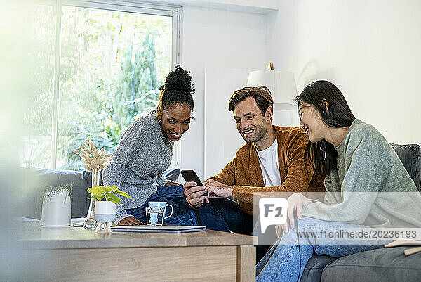 Small group of friends gathered in living room while using smart phone