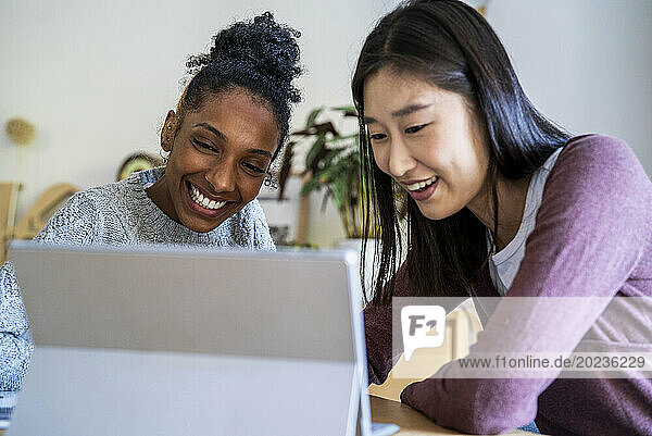Portrait of two females coworkers sitting at desk using digital tablet