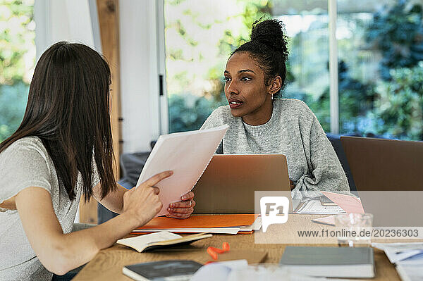 Two women discussing over paper work and laptop