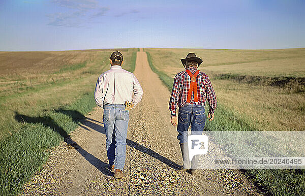 Rancher and his son walk down a gravel road; Howes  South Dakota  United States of America