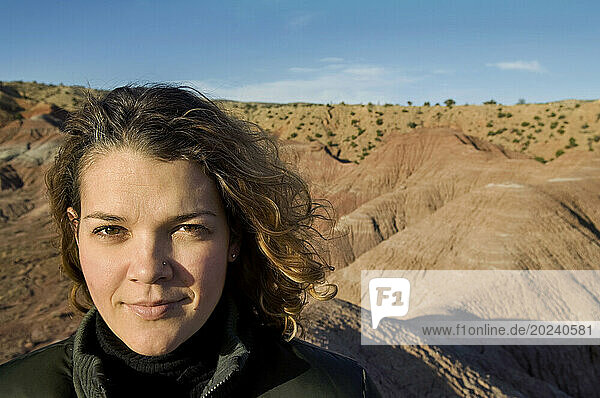 Outdoor portrait of a young woman with curly hair  posing atop a rock outcropping at Ghost Ranch near Santa Fe; New Mexico  United States of America