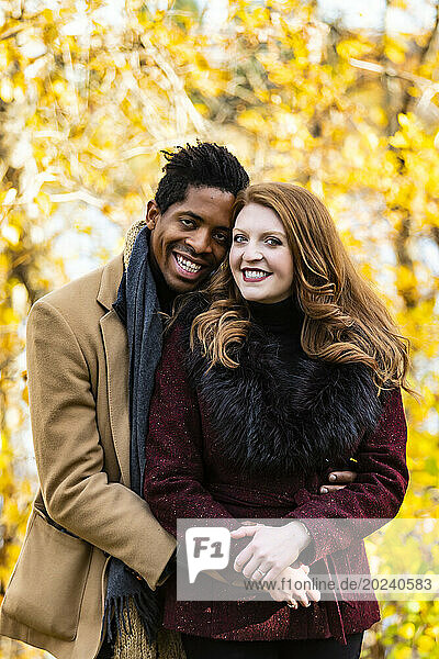 Close-up portrait of a mixed race married couple smiling at the camera while spending quality time together during a fall family outing in a city park; Edmonton  Alberta  Canada