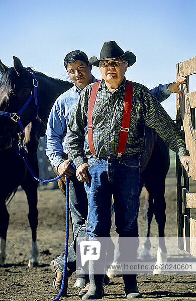 Rancher and his son with horses at a corral gate; Howes  South Dakota  United States of America
