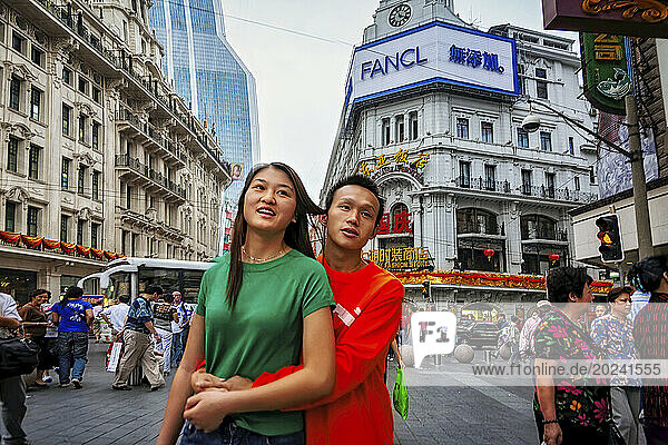 Teenage couple standing in an embrace on East Nanjing Road  the world's longest shopping precinct in Shanghai  China. It is around 6 km long and attracts over 1 million visitors daily; Shanghai  People's Republic of China