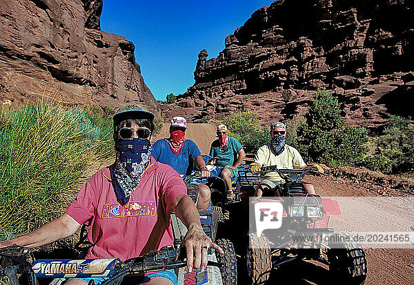 Bandit-style bandanas shield law abiders from dust on a well-worn trail in the Fisher Towers region of the Castle Valley near Moab  Utah. Off-road vehicle riders who stick to BLM's loosely enforced straight-and-narrow rules are plentiful  but thousands more disregard the rules  answering the call of their combustion engines to chart new paths through roadless areas. The degradation from rogue ATV riders has growing ecological consequences. Near Moab  Utah  USA; Utah  United States of America