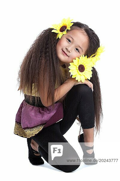 Porträt von Mode asiatischen kleinen Mädchen sitzen auf dem Boden mit Sonnenblume im Kopf. vor weißem Hintergrund